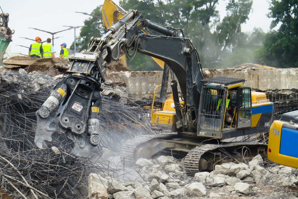 Chantier de démolition avec une machine équipé d'une pince broyeur de béton.